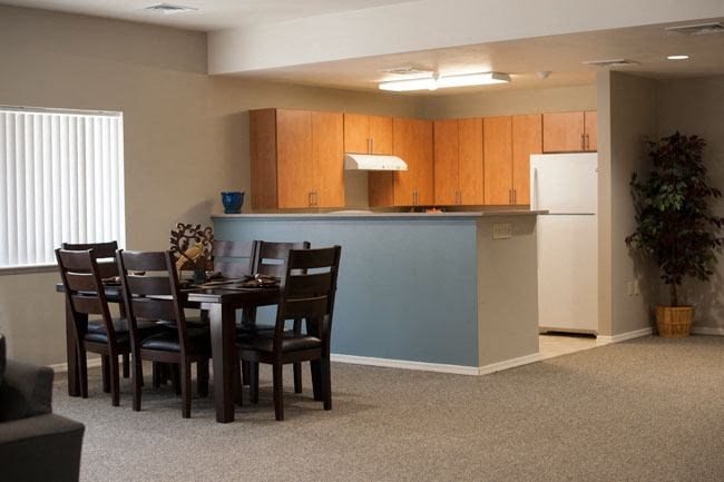 a dining area with a table and chairs and a kitchen in the background
