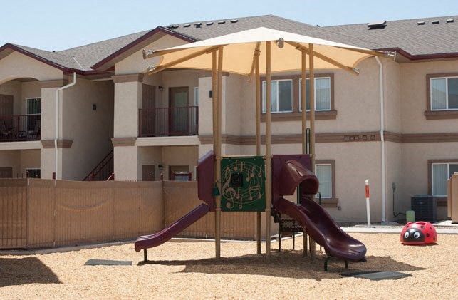 a playground with two slides and an umbrella