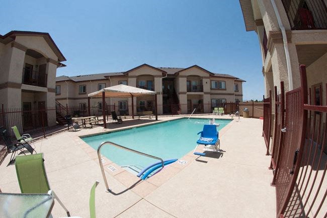 a swimming pool with chairs and umbrellas in front of a building