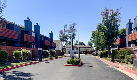 A street view of a residential area with houses on both sides and a sign in the middle of the road.