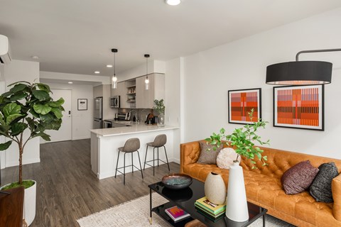 a living room and kitchen with white walls and wood flooring