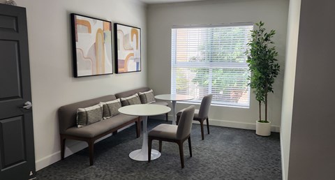 A grey sofa with a white table and two chairs in a room.