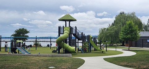 A playground with a green slide and a walkway.