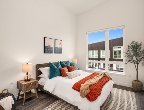 A bedroom with a large bed and a window overlooking a building.