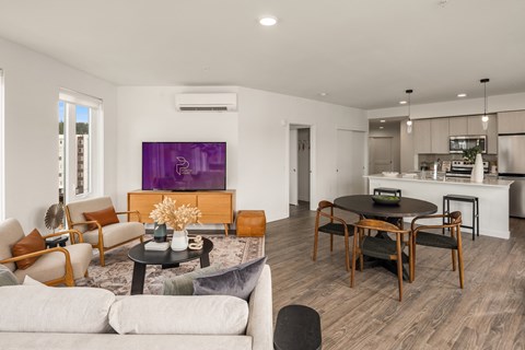a living room and kitchen area with white walls and hardwood floors