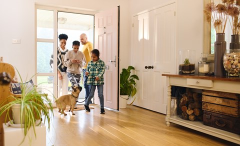 A family of four is standing in a living room with a dog.
