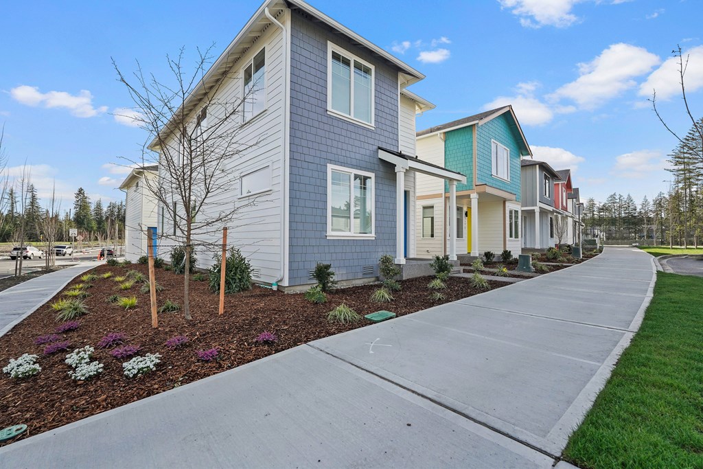 A row of houses with a sidewalk in front.