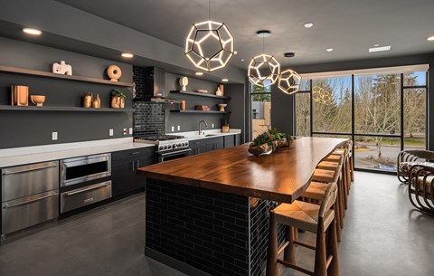 A modern kitchen with a long wooden table and stools.