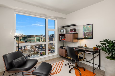 an office with a large window and a desk with two black chairs