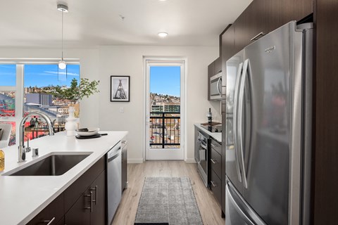 a kitchen with stainless steel appliances and a door to a balcony