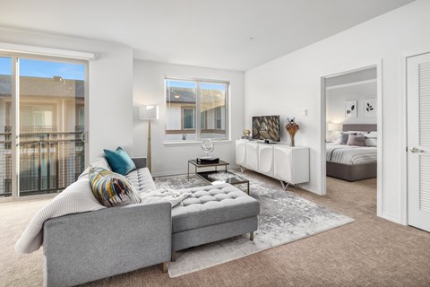 a living room with a couch and a chair and a door to a bedroom