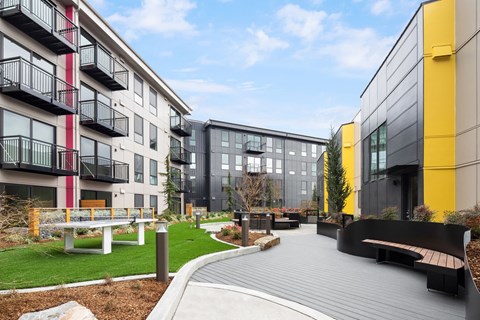 a courtyard with benches and grass in the middle of modern buildings