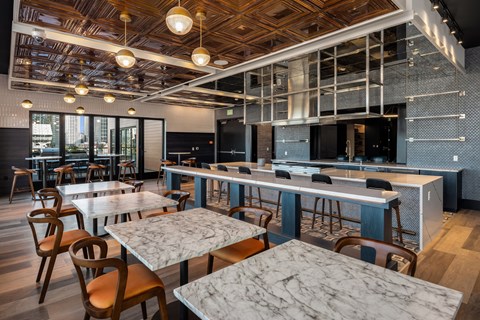 a dining room with marble tables and chairs and a large kitchen