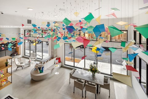 a room with tables and chairs and colorful umbrellas hanging from the ceiling