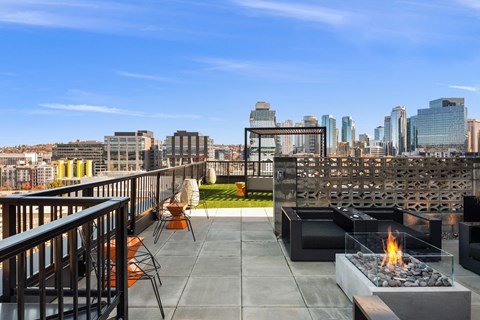 a rooftop deck with a fire pit and a view of the city
