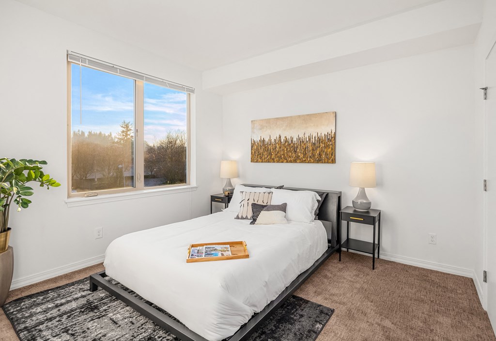 a white bedroom with a large window and a white bed