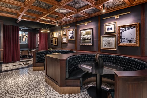 a bar with leather seats and a wooden table in a room with paintings