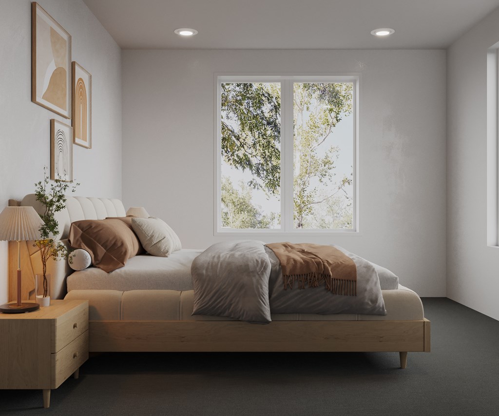 A bedroom with a large bed and a window showing trees outside.