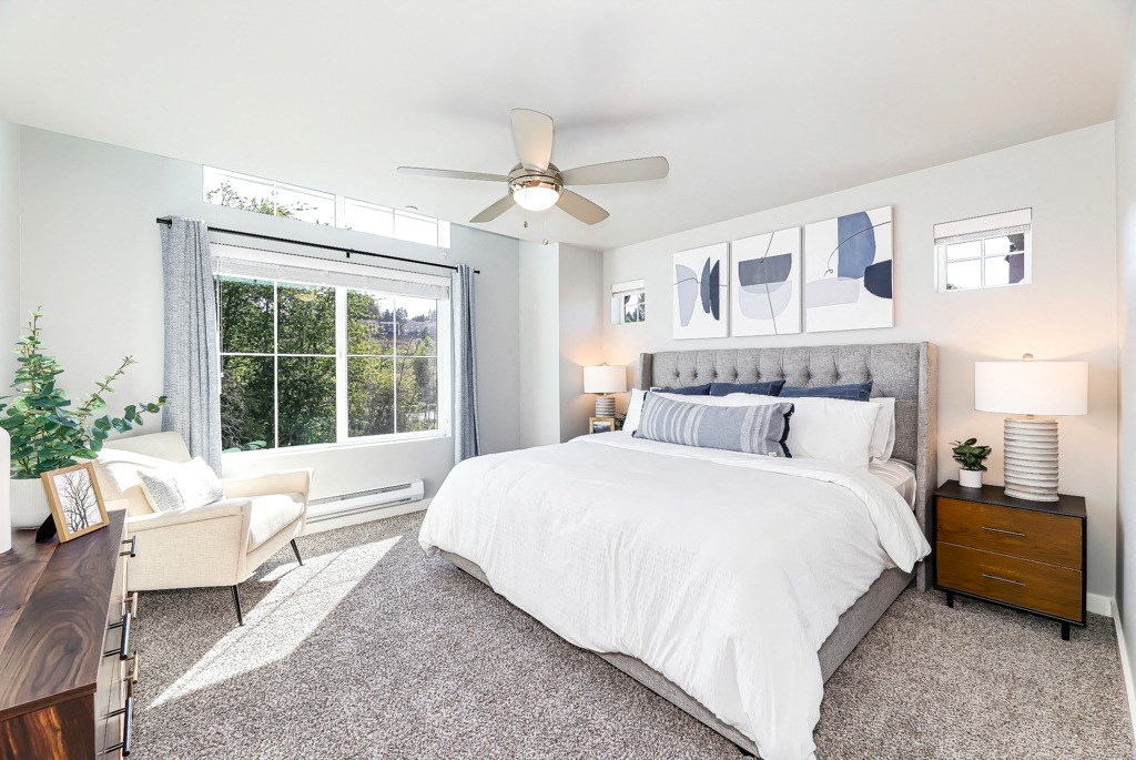 a bedroom with a large window and a ceiling fan