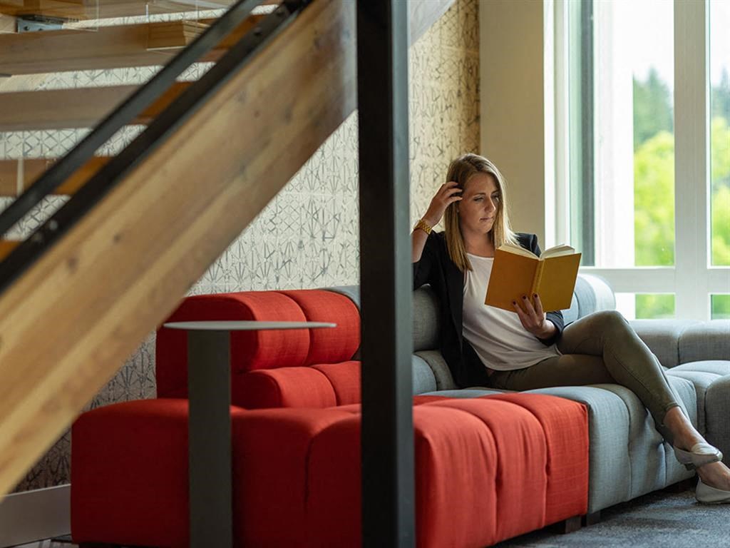 a woman sitting on a couch reading a book