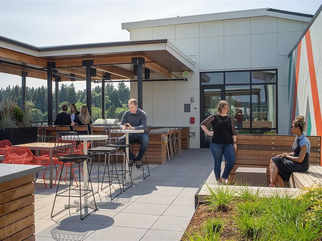 people sitting at tables on a patio outside of a building