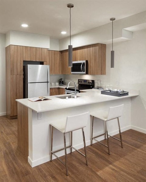 a kitchen with a large island with two white chairs