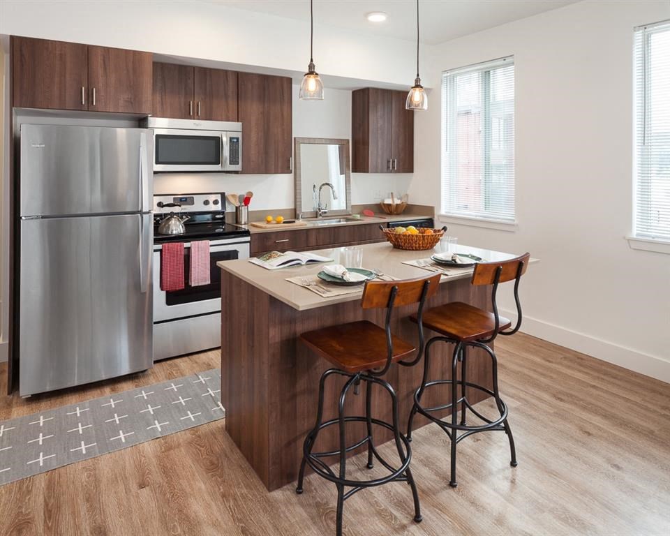 a kitchen with a center island and a stainless steel refrigerator