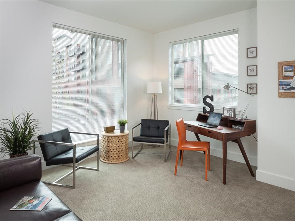 a living room with a desk and two windows