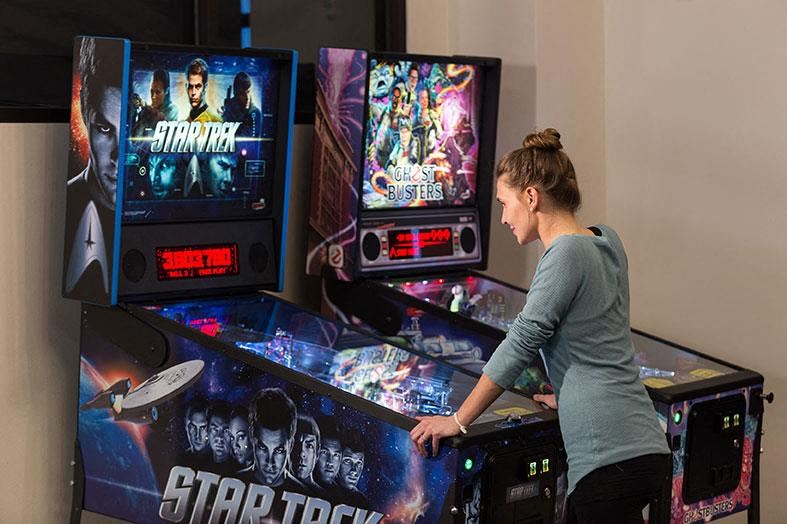 a woman is standing in front of a star wars arcade game