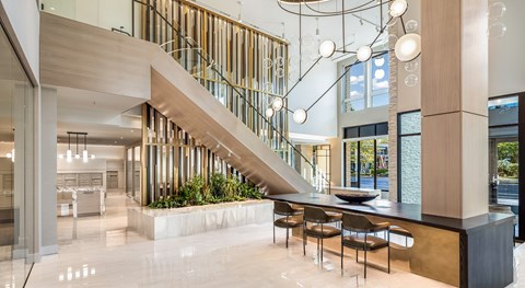 A modern interior space with a staircase, tables, and chairs.