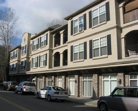 A row of townhouses with cars parked in front.