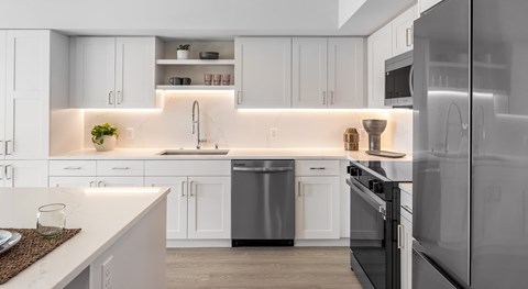 A modern kitchen with white cabinets and stainless steel appliances.