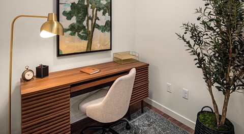 A desk with a chair and a lamp in a room.