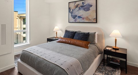A bedroom with a large bed and a painting on the wall.