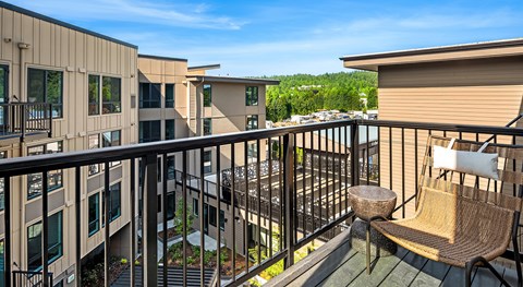 A balcony with a chair and table overlooking a courtyard.