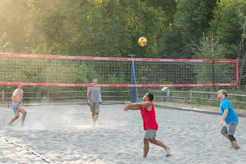 A group of people playing volleyball on a sandy court.
