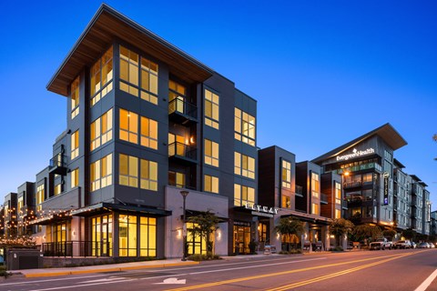 A modern multi-story building with a dark facade and lit windows.