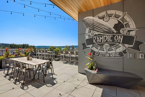 A patio area with tables and chairs and a mural on the wall.