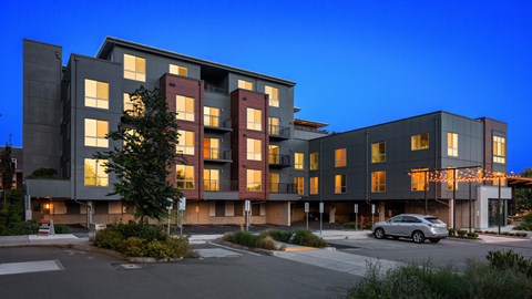 A modern apartment building with a parking lot in front.