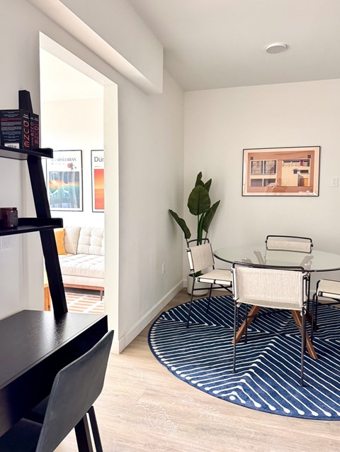 A living room with a white chair and a blue and white rug.