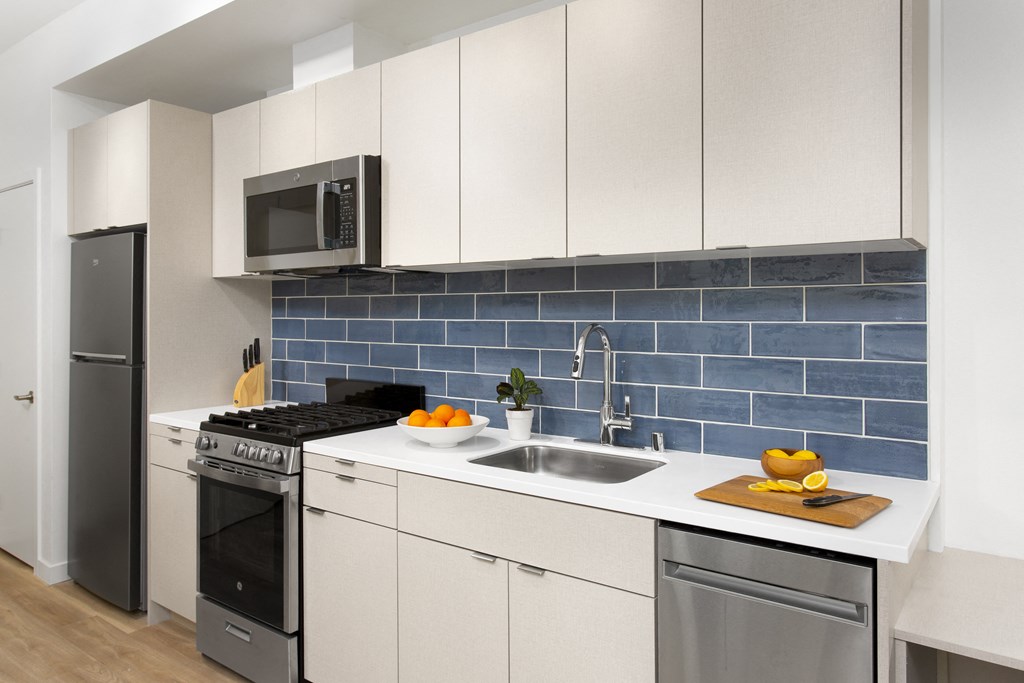 a kitchen with white cabinets and a blue subway tile