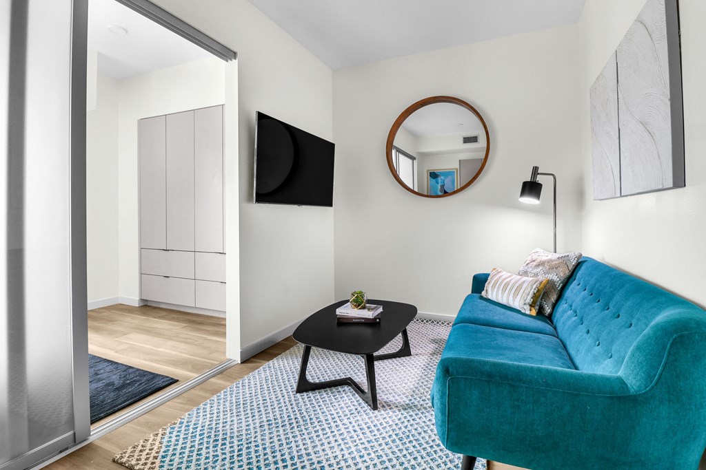 a living room with a blue couch and a round mirror on the wall