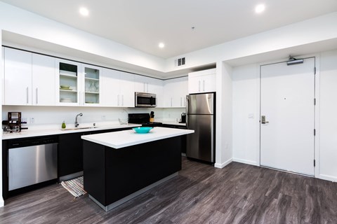 a kitchen with white cabinets and a black counter top and a stainless steel refrigerator