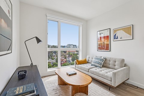 A living room with a couch, a coffee table, and a large window overlooking a cityscape.