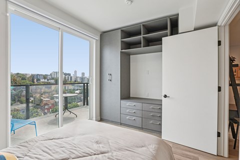 A bedroom with a large bed and a balcony overlooking a cityscape.