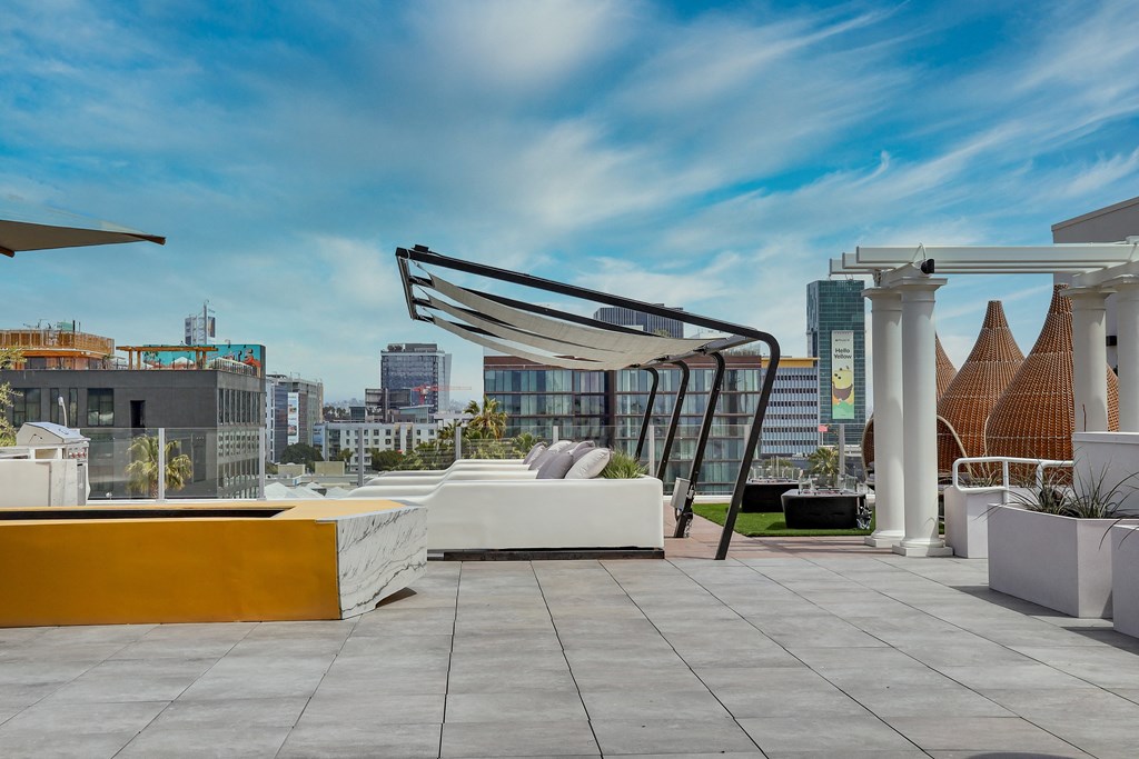 an outdoor terrace with a white couch and yellow table with white pillows and a white