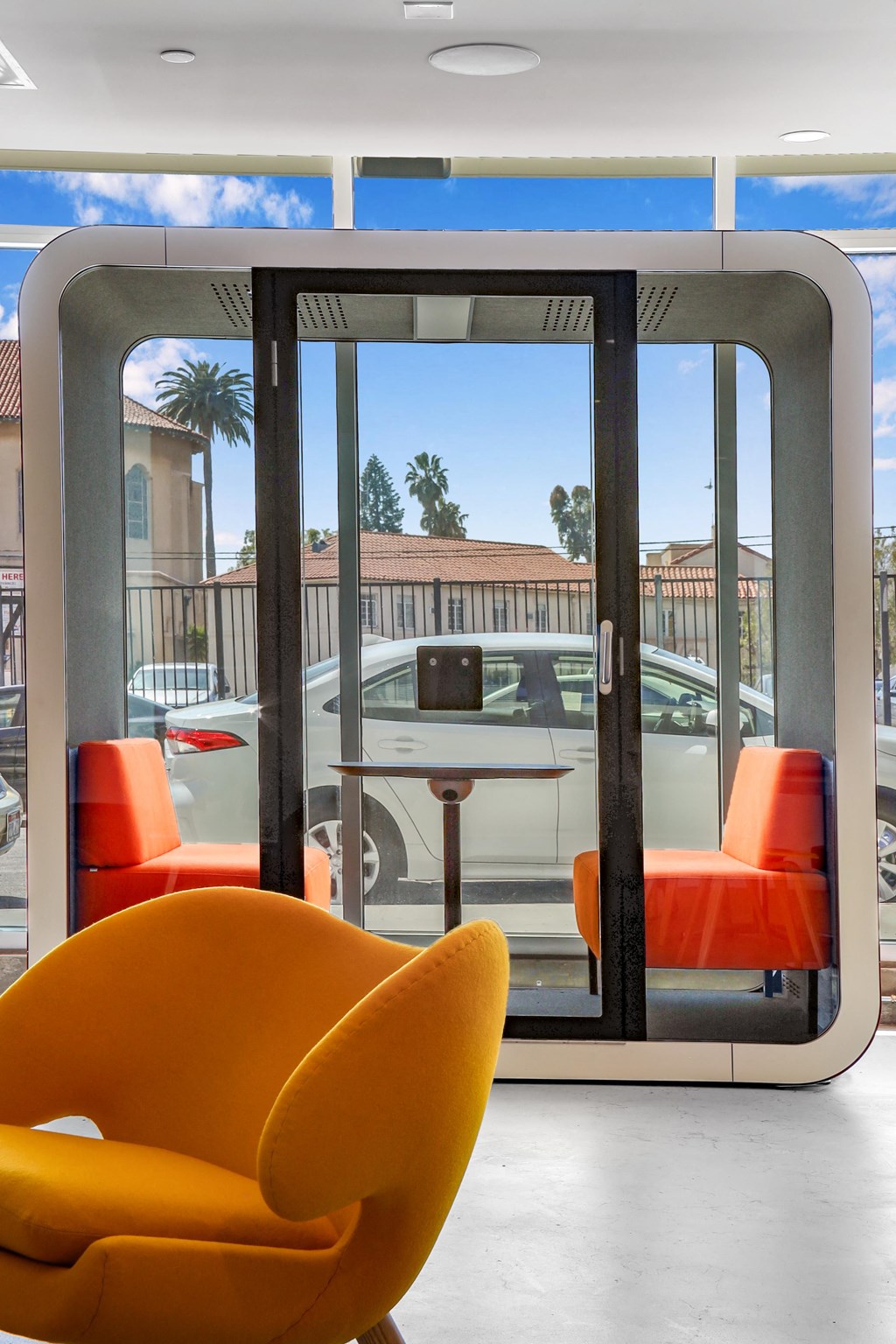 a seating area with orange chairs and a table in front of a window