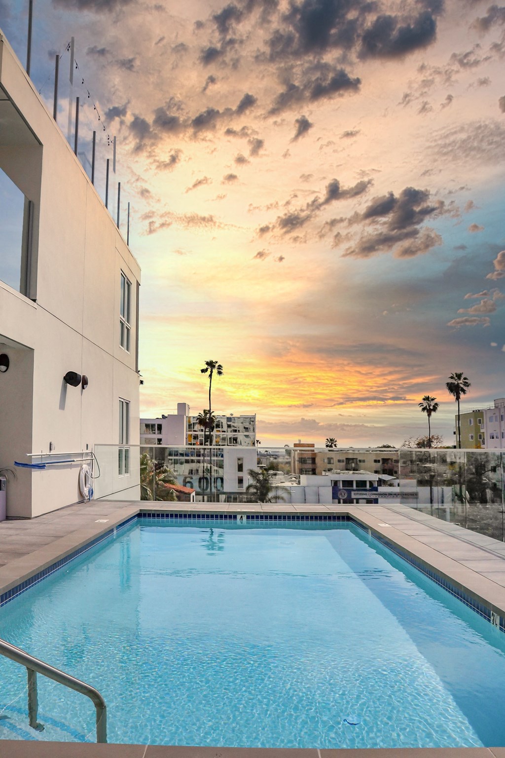 a view of the pool and sunset from a hotel room