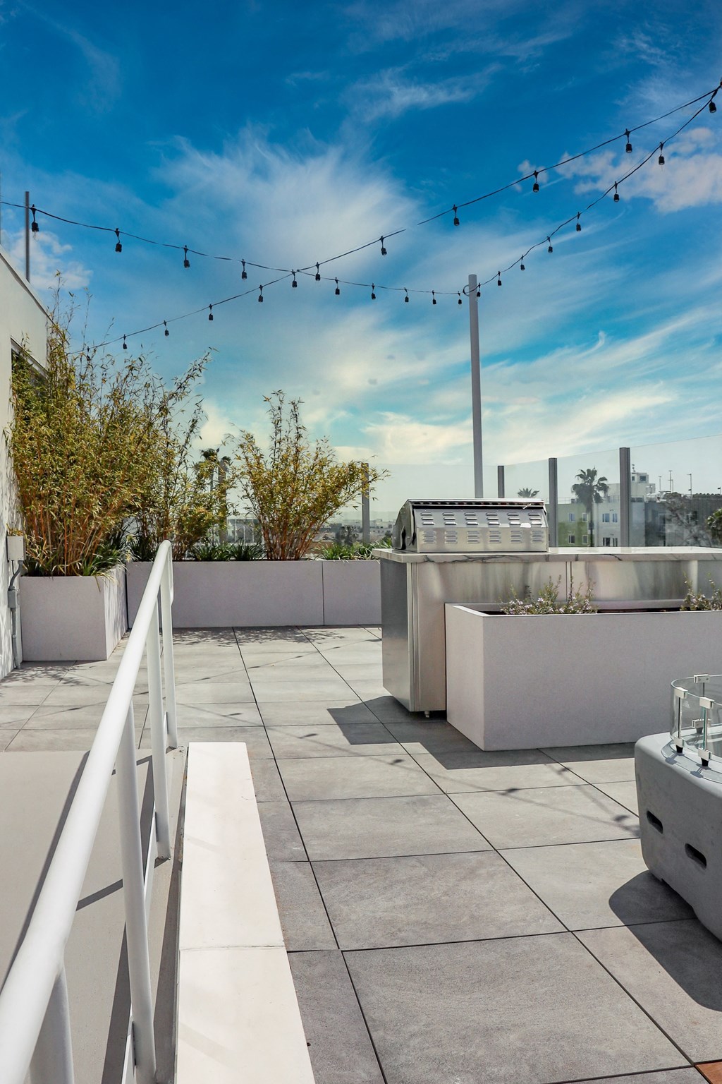 a rooftop terrace with a barbecue grill and a string of lights