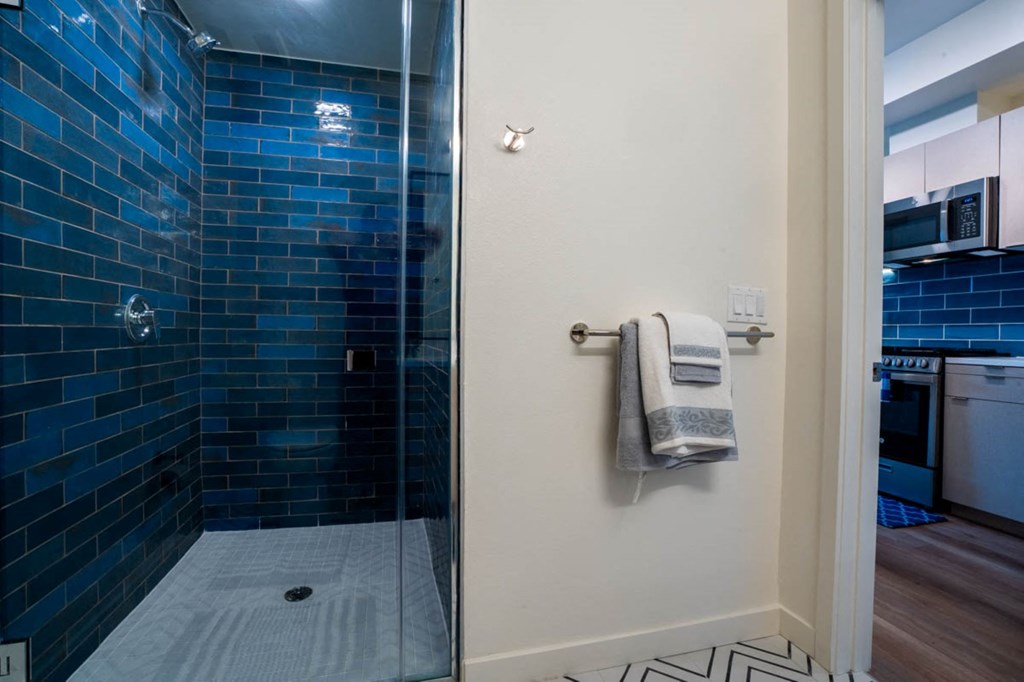 a bathroom with a glass shower and blue tiles